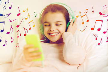 Image showing girl with headphones listening to music in bed