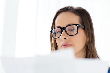 Image showing businesswoman in glasses reading papers at office