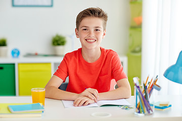 Image showing happy student boy writing to notebook at home
