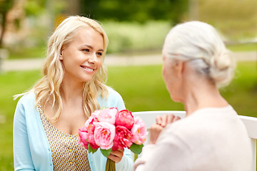 Image showing daughter giving flowers to senior mother at park