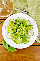 Image showing Salad from spinach and cucumber with cedar nuts on board top