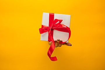 Image showing close-up of female hand holding a present through a torn paper, isolated