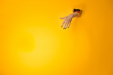 Image showing Woman hand making sign through a hole in paper