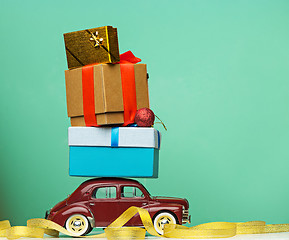 Image showing Blue retro toy car delivering Christmas or New Year gifts, on yellow