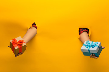 Image showing close-up of female hand holding a present through a torn paper, isolated