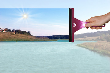 Image showing A hand washes a dirty window