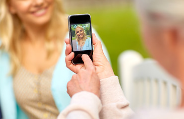 Image showing senior mother photographing daughter by smartphone