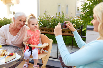 Image showing woman photographing her family at cafe