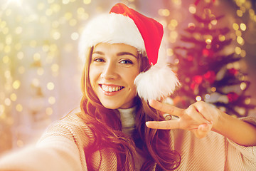 Image showing happy woman taking selfie over christmas tree