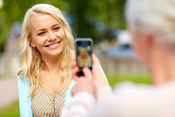 Image showing senior mother photographing daughter by smartphone