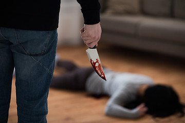 Image showing criminal with knife and dead body at crime scene