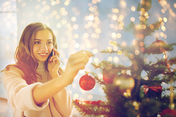 Image showing woman with smartphone decorating christmas tree