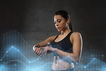 Image showing young woman with heart-rate watch in gym
