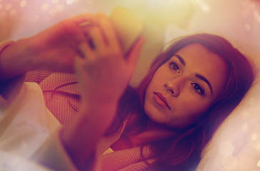 Image showing young woman with smartphone in bed at home bedroom