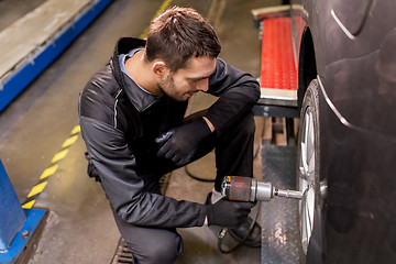 Image showing auto mechanic with screwdriver changing car tire