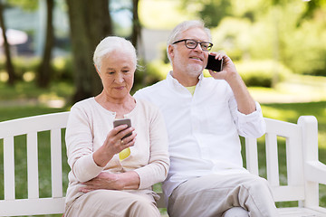 Image showing happy senior couple with smartphones at park