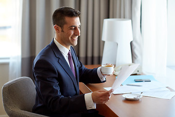 Image showing businessman with papers drinking coffee at hotel