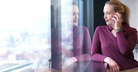 Image showing Elegant Woman Using Mobile Phone by window in office building