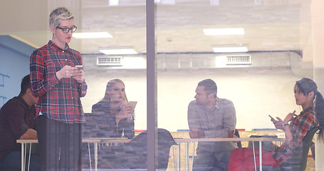 Image showing Business Woman Looking Through A Window And using On A Cell Phon