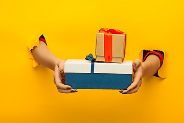 Image showing close-up of female hand holding a present through a torn paper, isolated