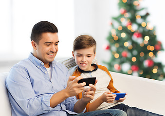 Image showing happy father and son with smartphones at christmas