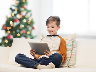 Image showing smiling boy with tablet pc at home at christmas