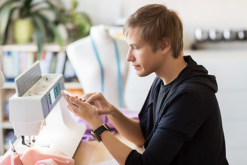 Image showing fashion designer with smartphone working at studio