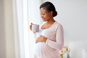 Image showing happy pregnant woman with cup drinking tea at home