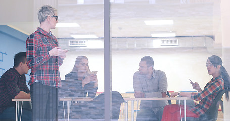 Image showing Business Woman Looking Through A Window And using On A Cell Phon