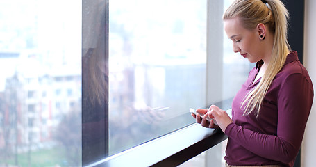 Image showing Elegant Woman Using Mobile Phone by window in office building