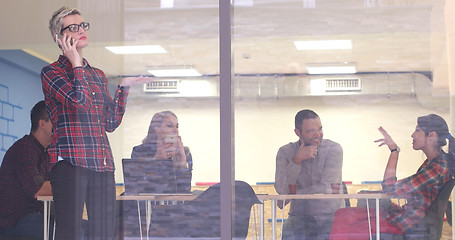 Image showing Business Woman Looking Through A Window And using On A Cell Phon