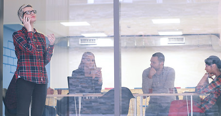 Image showing Business Woman Looking Through A Window And using On A Cell Phon