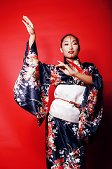 Image showing young pretty geisha on red background posing in kimono, oriental people concept close up