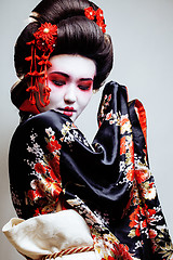 Image showing young pretty geisha in kimono with sakura and red decoration design on white background