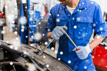 Image showing mechanic man with wrench repairing car at workshop