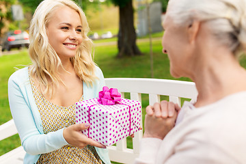 Image showing daughter giving present to senior mother at park