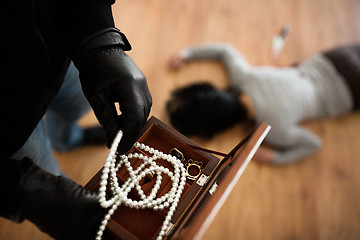 Image showing criminal with knife and jewelry at crime scene