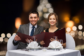 Image showing smiling couple with menus at christmas restaurant