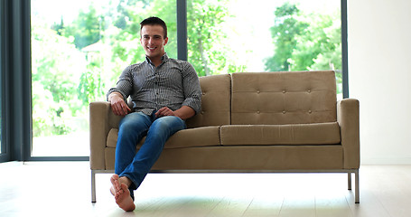 Image showing Man is Laying on Couch at Home and Using Tablet