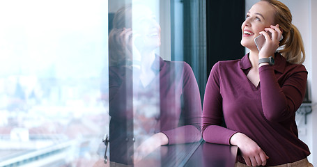 Image showing Elegant Woman Using Mobile Phone by window in office building