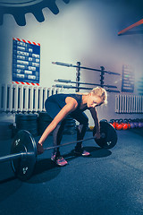 Image showing Fit young woman lifting barbell working out in a gym