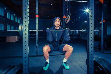 Image showing Portrait of super fit muscular young man working out in gym with barbell