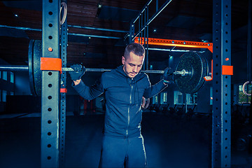 Image showing Portrait of super fit muscular young man working out in gym with barbell