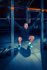 Image showing Portrait of super fit muscular young man working out in gym with barbell