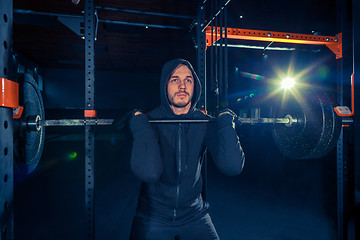 Image showing Portrait of super fit muscular young man working out in gym with barbell