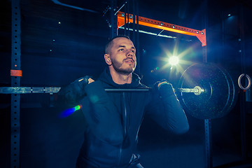 Image showing Portrait of super fit muscular young man working out in gym with barbell