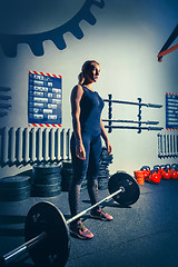 Image showing Fit young woman lifting barbells working out in a gym