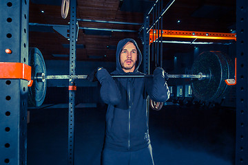 Image showing Portrait of super fit muscular young man working out in gym with barbell