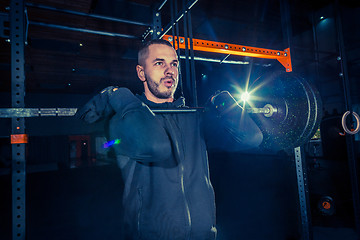 Image showing Portrait of super fit muscular young man working out in gym with barbell