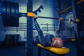 Image showing Portrait of super fit muscular young man working out in gym with barbell